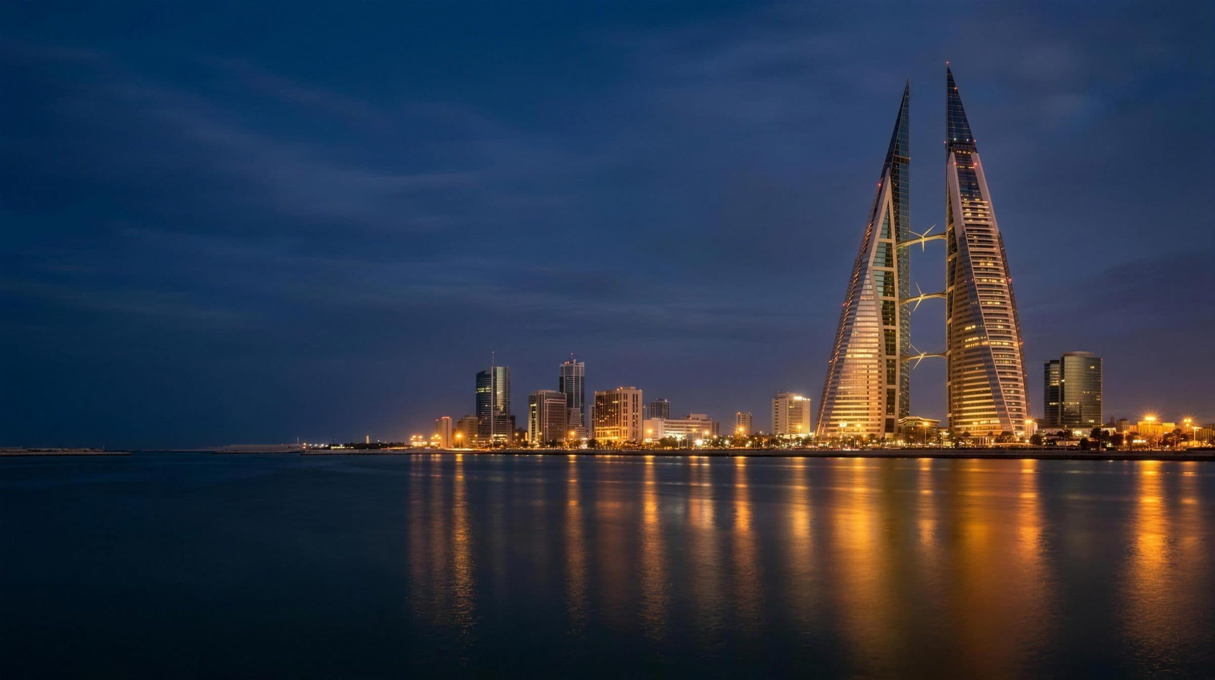 Manama skyline at blue hour with the Bahrain World Trade Center glowing gold over the water
